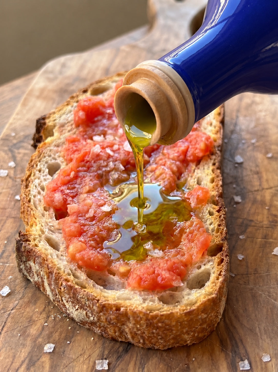 Aceite de oliva virgen extra 1490 cayendo sobre una tostada de pan con tomate