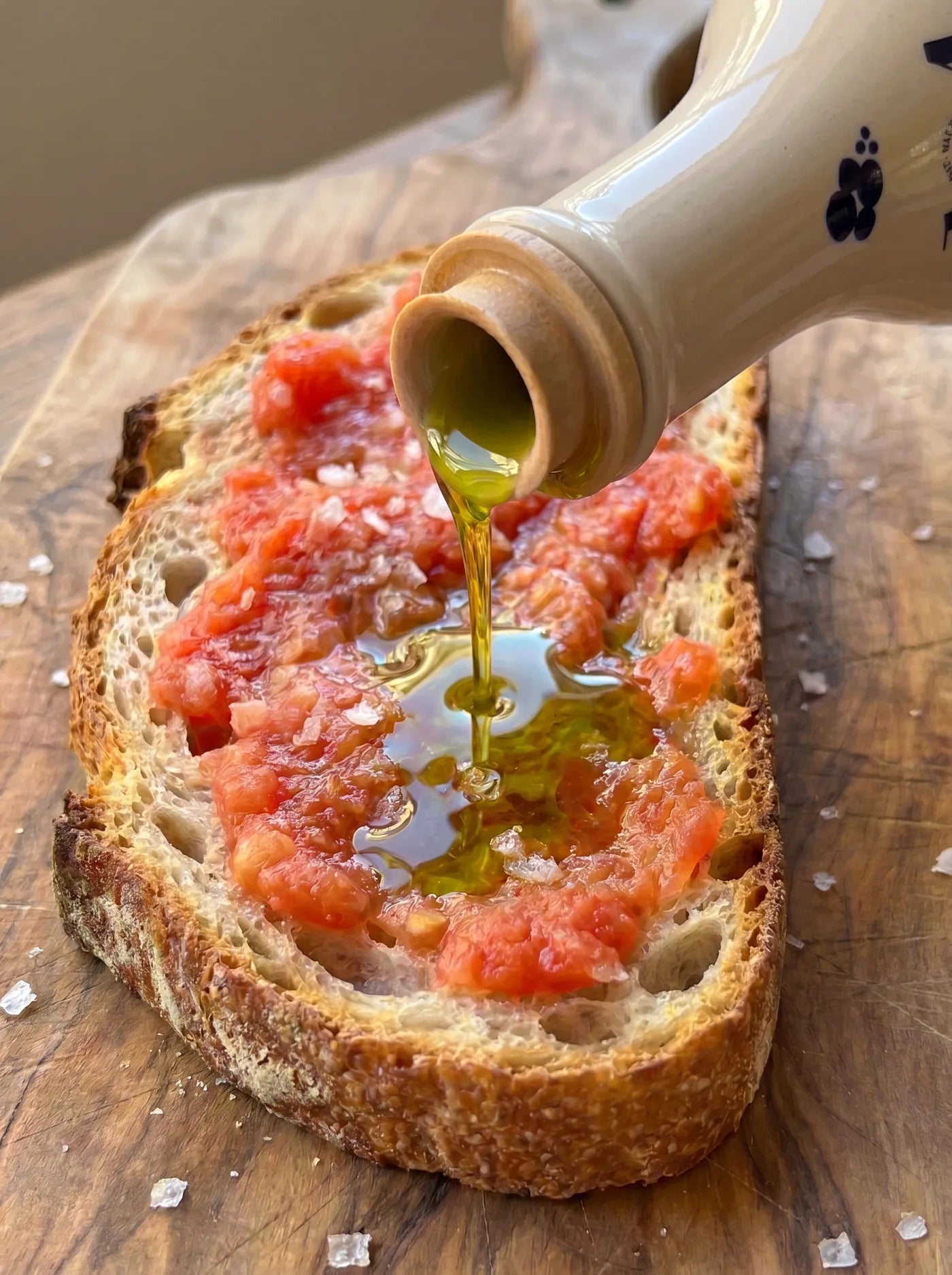 Aceite de oliva virgen extra ecologico cayendo desde la frasca sobre pan con tomate