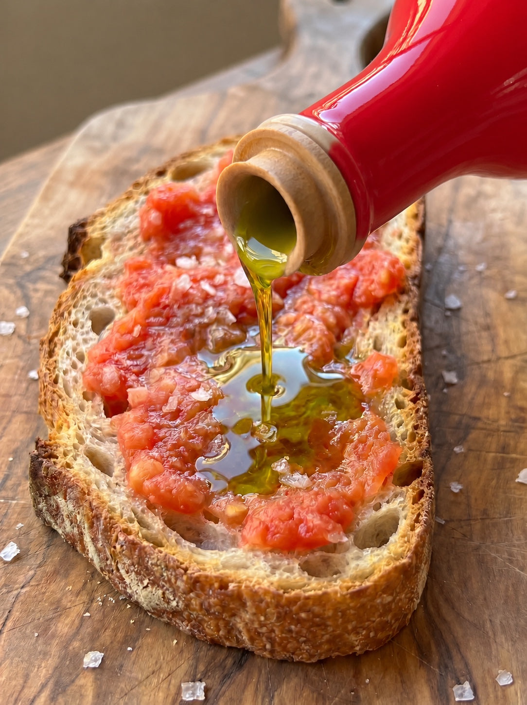 Aceite de oliva virgen extra 1490 cayendo sobre una tostada de pan con tomate