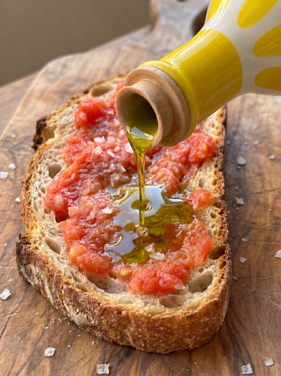 Aceite de oliva virgen extra 1490 cayendo sobre una tostada de pan con tomate